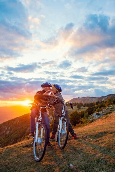 Pareja mayor activa en bicicletas haciendo forma de corazón con las manos y besándose. —  Fotos de Stock