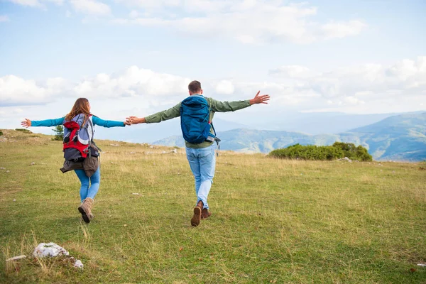Happy travelers couple conquered top of mountain, raises hands up — Stock Photo, Image