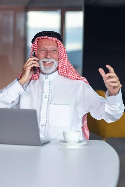 Ordenador portátil árabe hombre de negocios en la oficina moderna usando el teléfono — Foto de Stock