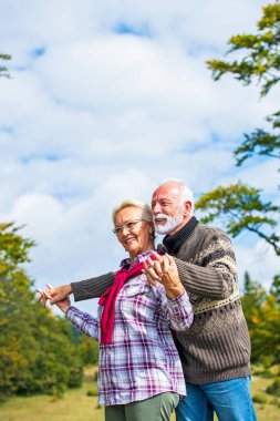 Sonbahar parkında kucaklaşan yaşlı çift. Aşkın tadını çıkarıyorum.