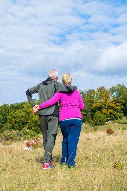 Arka portre. Son sınıf çifti güzel bir doğayla yürüyor..