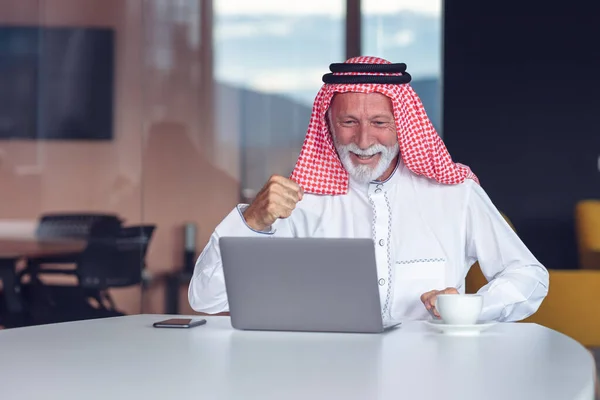 Hombre de negocios árabe celebrando la victoria en la oficina con el ordenador portátil. — Foto de Stock