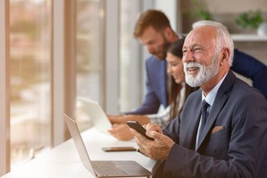 Üst düzey yönetici arka planda genç dilleri olan bir dizüstü bilgisayar kullanıyor.