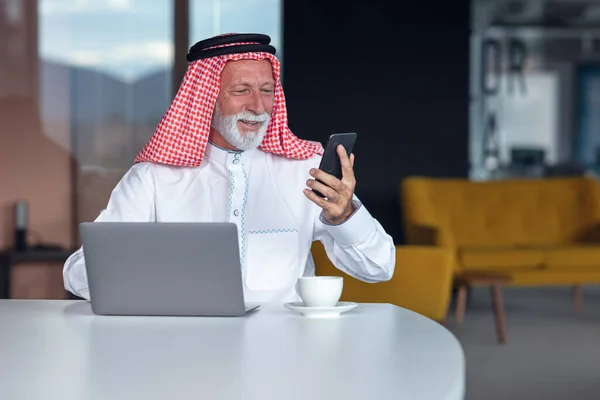 阿拉伯商人笔记本电脑在现代办公室使用电话 — 图库照片