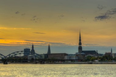 Riga 'daki nehir kıyısında gece görüşü yansıyor.