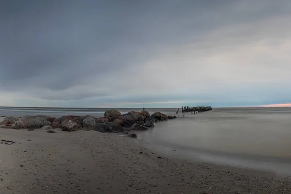 Restos de un viejo muelle, viejos puestos de escollera en la playa, Lapmezciems, Letonia — Foto de Stock