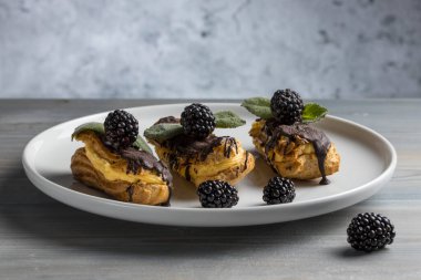 Geleneksel Fransız ekleride çikolata ve böğürtlen. Lezzetli tatlı. Ev yapımı kek ekler. Kremayla doldurulmuş tatlı pasta. Çikolata kreması..