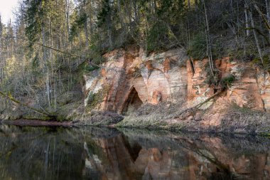 Kızıl kumtaşı kayalıkları Salaca nehrindeki melek mağarası.