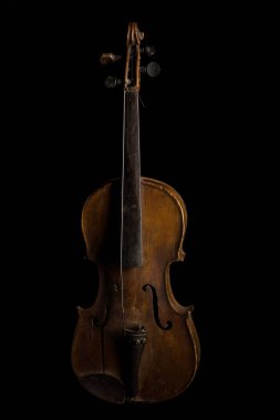 Antika ahşap bir keman, karmaşık tasarımı ve zengin tarihini gösteren siyah bir arka fona çarpıcı bir şekilde dayanır. Bu yıpranmış yüzey yılların müziğini anlatıyor..