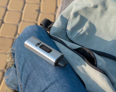 Taşınabilir bir bitkisel buharlaştırıcı bacağında bir adamın kotunun içinde duruyor.