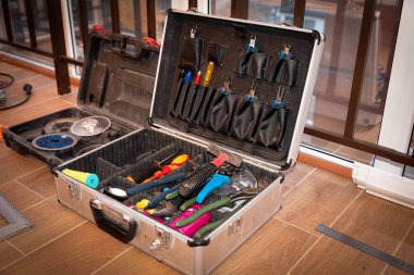 El aletleriyle dolu bir bavul pencerenin yanındaki odada, yerde.