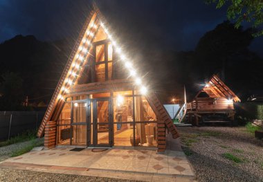 Teberda, Rusya 09,07,2021. Dağlardaki ahşap ev mavi gece gökyüzünün arka planına karşı..