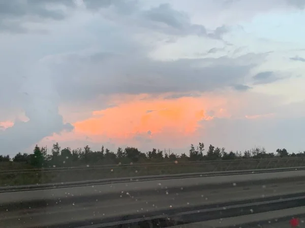 雨の中の夕日を背景にした道 — ストック写真