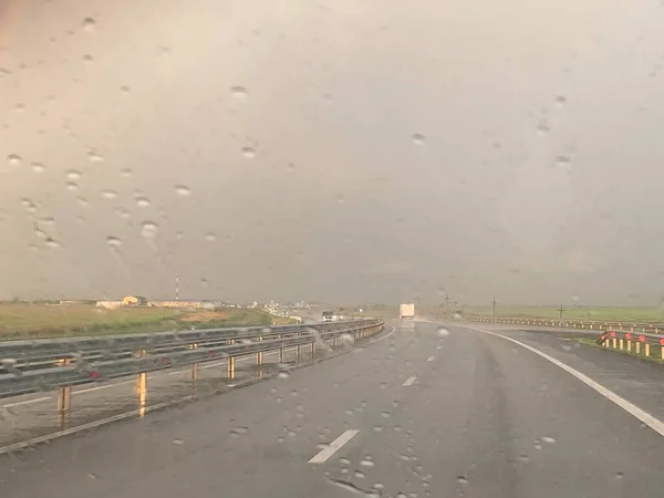 雨の中の夕日を背景にした道 — ストック写真