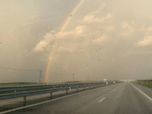 雨の後 ガラス越しに虹の景色を望む道 — ストック写真