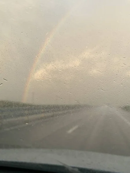 雨の後 ガラス越しに虹の景色を望む道 — ストック写真