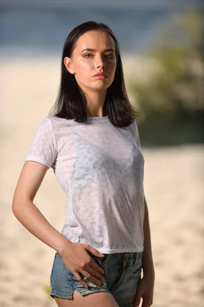Model pózuje na pláži v džínových kraťasech — Stock fotografie