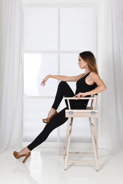 Pose de moda - mujer se sienta en la silla en pose modelo en tacones altos — Foto de Stock