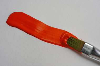 Boya fırçası kağıda turuncu çizgi uygular, yakın plan.