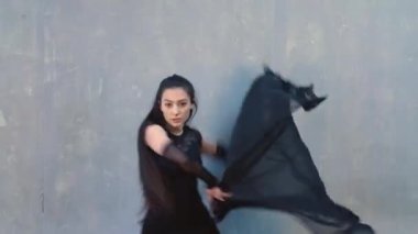 Duvarda bir kumaş parçasıyla hareket eden kadın dansçı. Salon dansı..