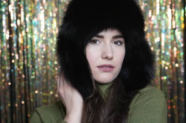 Kış kürklü kadın portresi. Yüzü ve elleri ışıltılı arka planda.