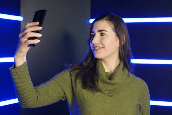 Κορίτσι βγάζει selfie στο τηλέφωνο με φόντο νέον φώτα — Φωτογραφία Αρχείου