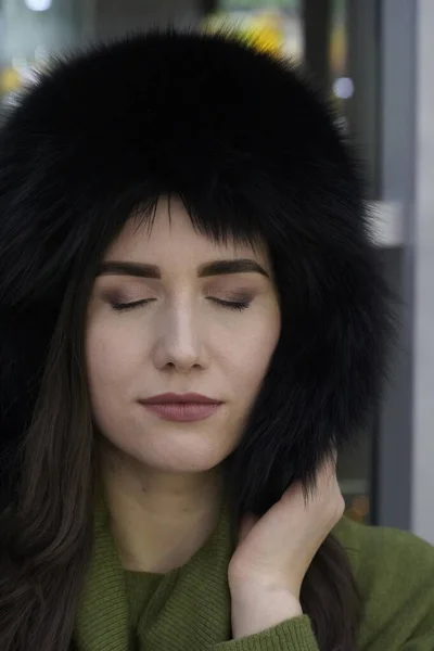 Retrato de mulher de estilo casual com os olhos fechados em chapéu de pele de inverno close-up, rosto e mãos em fundo brilhante — Fotografia de Stock