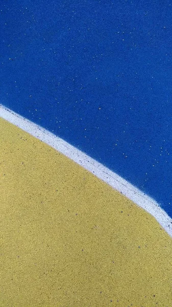 Textura del revestimiento pintado del campo de deportes - amarillo, azul, blanco —  Fotos de Stock