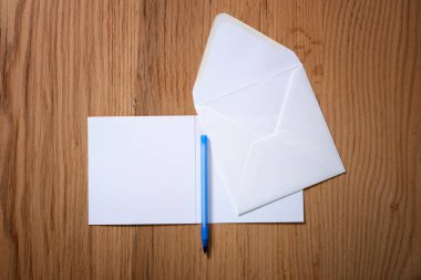 Tahta bir arka planda zarf, kalem ve harf.