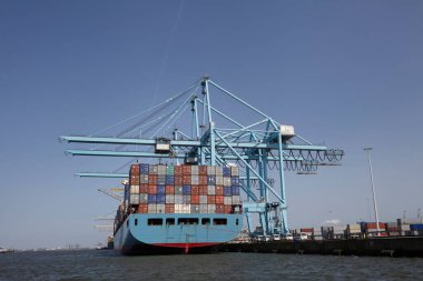 Rotterdam, Hollanda. Konteynır terminalindeki büyük bir konteynırın görüntüsü konteynırların yanına demirlenmiş karada ve nehir mavnasında yükleme ve boşaltma konteynırları.