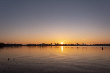 Kralingse Plas 'tan (Kralingen Gölü) görüleceği gibi Rotterdam ufuk çizgisinde gün batımı gölün durgun sularına yansıyan renkli gökyüzü