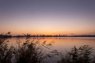 Kralingse Plas 'tan (Kralingen Gölü) görüleceği gibi Rotterdam ufuk çizgisinde gün batımı gölün durgun sularına yansıyan renkli gökyüzü