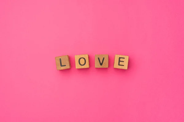 Wooden cubes with the word Love on an empty colorful pink background. Word of love are made of letters from wood for your girlfriend, boyfriend, wife, husband, for Valentines Day greeting romantic — Stock Photo, Image