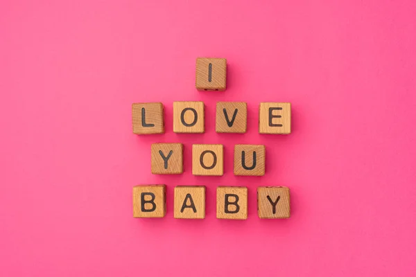Houten blokjes met de zin I Love You Baby op een lege kleurrijke roze achtergrond. Woorden van liefde zijn gemaakt van brieven van hout voor je vriendin, vriend, vrouw, echtgenoot, voor Valentijnsdag — Stockfoto