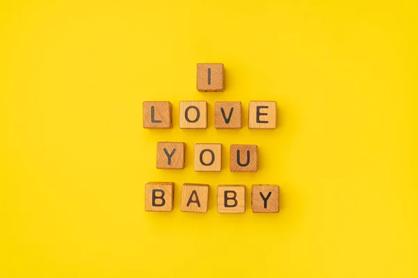 Houten blokjes met de zin I Love You Baby op een lege kleurrijke gele achtergrond. Woorden van liefde zijn gemaakt van brieven van hout voor je vriendin, vriend, vrouw, echtgenoot, voor Valentijnsdag — Stockfoto