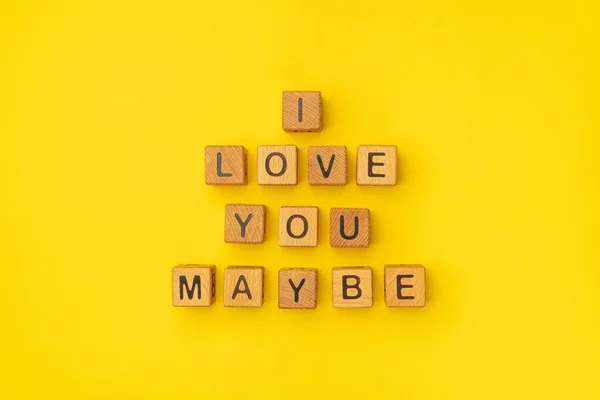 Houten blokjes met de zin I Love You Maybe op een lege kleurrijke gele achtergrond. Woorden van liefde zijn gemaakt van brieven van hout voor je vriendin, vriend, vrouw, echtgenoot, voor Valentijnsdag — Stockfoto