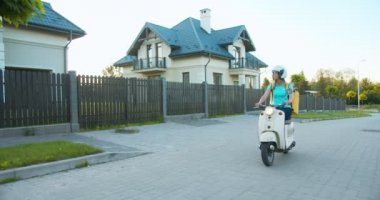 Beyaz kadın teslimat işçisi scooterla caddeye inip müşteri adresini arıyor. Kasklı ve termal sırt çantalı bir kız kurye sipariş veriyor. E-ticaret ve online alışveriş