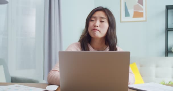 Jovem bonita sentada à mesa, trabalhando na sala de escritório moderna. Pensativo asiático designer feminino, arquiteto, jornalista pensando, digitando no computador portátil. Auto-isolamento durante a pandemia. — Vídeo de Stock