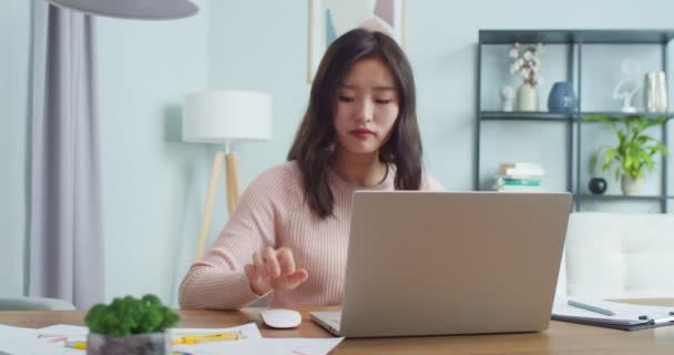 Mulher asiática bonita trabalhando e estudando em home office. Inteligente jovem operária abrindo laptop para trabalhar e estudar usando o mouse, digitando no quarto com design minimalista moderno. Carreira, conceito de educação. — Vídeo de Stock