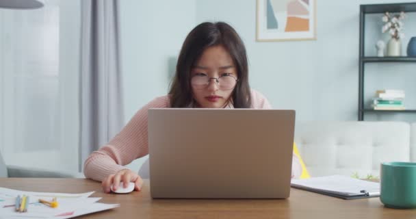 Jornalista nervosa em óculos sentada à mesa e trabalhando em casa. Jovem mulher asiática usando laptop, sendo louco, com raiva por causa do fracasso. Atividade estressante, problemas de negócios. — Vídeo de Stock