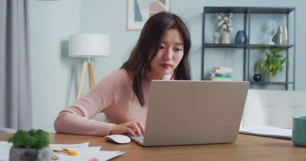 Estudante asiática entusiasmada recebendo e-mail do Conselho de Admissão da universidade em casa. Jovem encantadora a ler mensagens e a ser feliz. Ensino superior. Interior minimalista moderno. — Vídeo de Stock