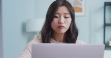 Modern minimalist tasarıma sahip güzel bir Asyalı kadının ev ofisinde çalışmasına yakın çekim. Genç bayan serbest çalışan dizüstü bilgisayar açıyor, işe başlıyor. İş, meslek, iş kavramı.