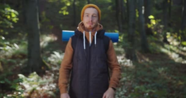 Close up portrait of hipster with piercing standing in forest crossing arms and smiling. Man tourist looking at camera on woods landscape. Concept of people traveling in nature. Journey in Wildlife — Stock Video