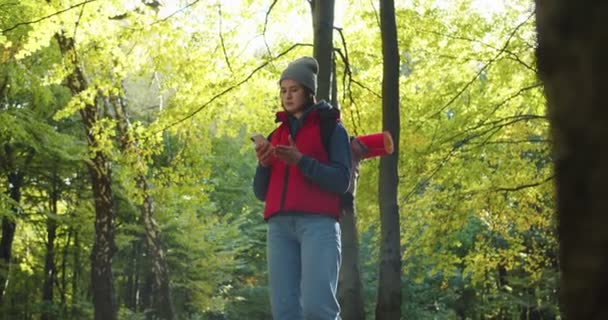 Middle plan of beautiful woman traveler trying to catch cell signal on phone in forest, no signal on phone. Female tourist on background of woods landscape. Concept of people traveling in nature. — Stock Video