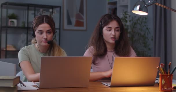 Kafkasyalı güzel ikiz kardeşler rahat bir odada, başlık takmış dizüstü bilgisayarlarda video konuşmaları yapıyorlar. Ev mesafesindeki bilgisayarlar üzerinde çalışırken görüntülü konuşma yapan kadınlar. E-öğrenme — Stok video