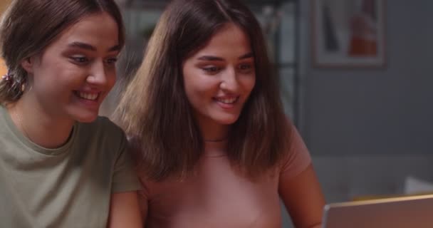 Primer plano retrato de caucásico feliz joven gemelos saludando las manos y sonriendo mientras habla en video llamada en línea en el ordenador portátil. Dos hermanas alegres que tienen chat web en el ordenador en casa. Concepto de ocio — Vídeo de stock