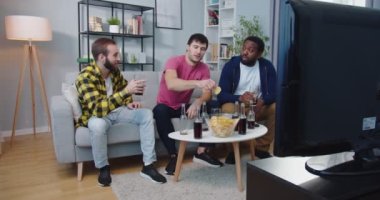 Çok ırklı erkek arkadaşlar, Kafkas ve Afro-Amerikalı erkekler, birlikte oturuyorlar, konuşuyorlar, abur cubur yiyorlar ve televizyon maçı izlerken içki içiyorlar. Eğlenceli konsept