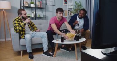 Üç tane çok ırklı erkek Kafkas ve Afro-Amerikalı en iyi arkadaş kanepede oturup sohbet ediyor, abur cubur yiyor ve televizyon izlerken içiyor. Arkadaşlık kavramı
