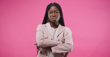 Stüdyoda pembe arka planda tek başına kameraya bakarken ciddi yüz ifadesi olan güzel Afro-Amerikan genç kadının portresi. Sadece pembe duvarda poz veren bir kadın.