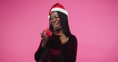 Noel Baba şapkalı, mutlu, neşeli, genç Afrikalı bir bayan yeni yıl süsleme oyuncağı şeklinde el bisküvisi tutarak 2021 'i kutluyor. Portreyi kapat
